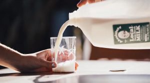 A glass being filled by a jug of milk.
