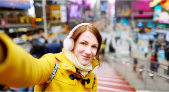 A young woman with headphones in a crowded Times Square.
