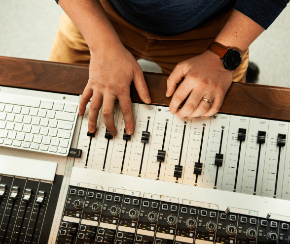 An audio producer adjusting levels on a sound board.